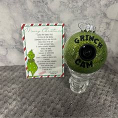 a grinch christmas ornament sitting on top of a table next to a card