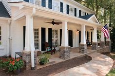 a white house with black shutters and an american flag on the front porch area