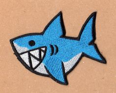 a blue and white shark embroidered on a brown surface