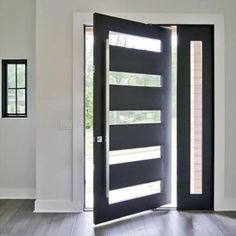 an open door in a white room with wood flooring and black glass inserts