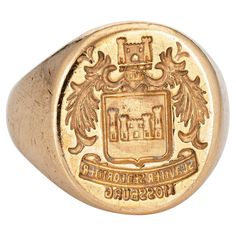 Finely detailed vintage Art Deco era family crest signet ring (circa 1920s to 1930s) crafted in 14 karat yellow gold. The signet ring weighs a hefty 18.7 grams. The signet mount features a castle framed with wreaths to the sides. The base of the signet mount reads in Latin the phrase 'suaviter sedfortiter' or 'Gently buy Bravely'. 'Mossburg' appears beneath and we believe this a reference to a family name. The low rise ring (4mm - 0.15 inches) sits comfortably on the finger. The ring is in very good condition. We have not cleaned it in order to preserve the patina and collector value. Particulars: Weight: 18.7 grams Stones: N/A. Size & Measurements: The ring is a size 9 3/4 (sizable). The mount measures 20mm in length (0.78 inches) and 18.5mm wide (0.72 inches) rising 3mm from the finger. Signet Rings Women Vintage, Family Seal, Family Crest Rings, Art Deco Jewelry Vintage, Medieval Rings, Signet Rings Women, Family Rings, Gold Signet Ring, Yellow Gold Jewelry