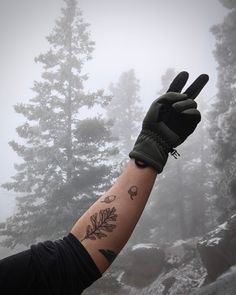 a person with a tattoo on their arm holding up a peace sign in the air