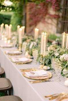 a long table is set with candles and flowers for an elegant wedding reception in the garden