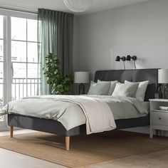 a bedroom with a bed, nightstands and plants on the wall next to it