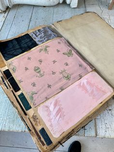 an old suitcase is sitting on the floor next to some other pieces of cloths