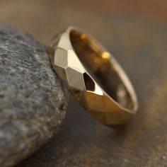 two gold wedding rings sitting on top of a rock