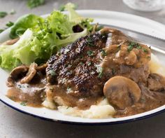 a white plate topped with meat covered in mushroom gravy