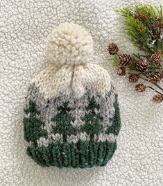 a green and white knitted hat next to pine cones