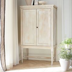 a white cabinet sitting next to a potted plant