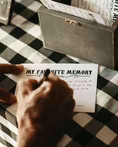 a person writing on a piece of paper next to a box with a note inside