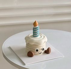 a small cupcake with a candle on top sitting on a white table next to a window