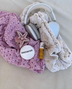 a pile of clothing and accessories laying on top of a white bed sheet next to an earbud