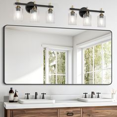 a bathroom vanity with two sinks and a large mirror above it, in front of a window