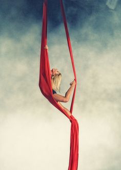 a woman is standing on a pole with her hands in the air and holding onto it