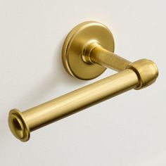 a gold toilet roll holder on a white wall