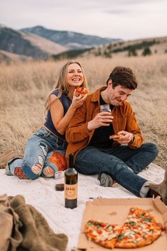 a man and woman sitting on the ground eating pizza