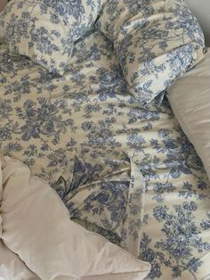 an unmade bed with blue and white floral comforter on it's side