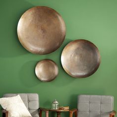 three metal plates mounted on the wall above two chairs and a small table in front of them