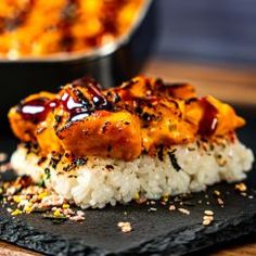 a black plate topped with rice covered in sauce