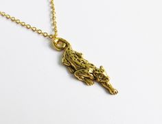 a gold plated necklace with an alligator on it's back and a chain that is attached to the neck