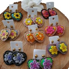 a wooden table topped with lots of different colored flowers and heart shaped brooches