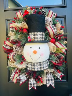 a christmas wreath with a snowman wearing a top hat and bow tie on the front door