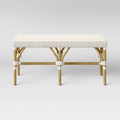 a white wicker bench sitting on top of a wooden table