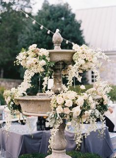 an outdoor fountain with flowers and greenery on it