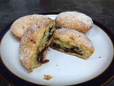 some powdered sugar filled pastries are on a black and white plate with one cut in half