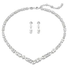 Exquisite refinement is brought to life in this show-stopping jewelry set from the Mesmera family. The necklace is made with a string of eye-catching Swarovski Zirconia on a rhodium plating setting, all produced in a surprising mix of cuts and sizes. For extra luxury, the elongation is completed with a lobster closure and a scattering of Swarovski Zirconia. The light-catching earrings are also rhodium plated, with a bold hanging design featuring luminous pear-cut crystals. Gift this set to a lov Swarovski Earrings Crystals, Swarovski Jewelry Set, Swarovski Necklace Crystal, Swarovski Jewelry Aesthetic, White Gold Jewelry Set, Swarovski Jewelry Necklace, Bride Jewelry Set, Necklace Luxury, Hanging Design