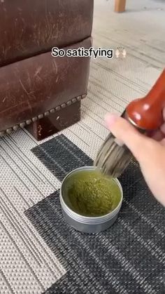 a person is using a brush to paint a green substance in a white bowl on the floor