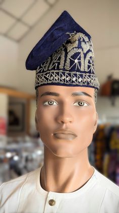 Introducing the exquisite Aṣọilu Navy-Blue and Silver Nigerian Velvet Fila Kufi Cap, a masterpiece of traditional craftsmanship and modern elegance, exclusively offered by Dupsie's African Fashion. This distinguished hat is not only a symbol of cultural heritage but also a fashion statement, meticulously designed for formal and special occasions. The Aṣọilu, translating to "Town's Cloth" in Yoruba, perfectly encapsulates the blend of tradition and contemporary fashion, making it a must-have acce Ceremonial Blue Adjustable Hat, Adjustable Blue Ceremonial Hats, Traditional Fitted Blue Hat, Traditional Festival Hat One Size, Traditional Fitted Headpiece For Festivals, Traditional Blue Cap, Traditional Adjustable Headpiece With Tall Crown, Ceremonial Costume Hat With Structured Crown, Adjustable Ceremonial Costume Hat With Structured Crown