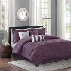 a bed with purple comforter and pillows in a room