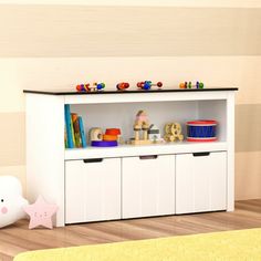 there is a white bookcase with toys on the top and drawers below it in this child's room