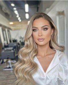 a woman with long blonde hair wearing a white shirt in an office setting and looking at the camera