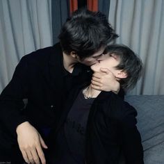 two people kissing each other while sitting on a couch