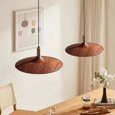 two wooden lamps hanging from the ceiling above a dining room table with flowers in vases