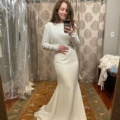 a woman taking a selfie in front of a mirror wearing a white dress and holding a cell phone