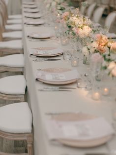 the long table is set with white linens and place settings