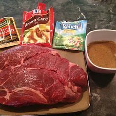 raw meat, spices and seasonings are on a plate next to a bowl of soup