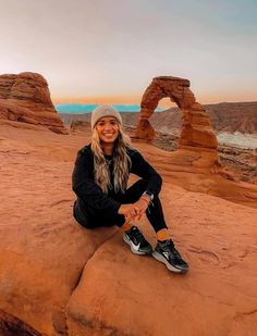 a woman sitting on top of a rock formation