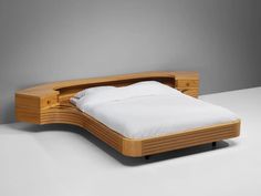 a bed that is made out of wood and has white sheets on the headboard