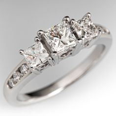 a three stone diamond ring with diamonds on the band and sidestones set in 18k white gold