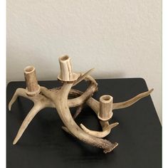 a sculpture made out of driftwood on top of a black table next to a white wall