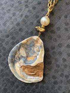 One of a kind handmade Oyster & Pearl Shell Necklace. An assemblage of pretty beads top this patterned oyster shell pendant: 12mm Pearl bead, faceted gold hematite bead and a chunky gold quartz nugget are all strung together on an 18K gold plated chunky paper clip style chain. The genuine oyster seashell has two unique sides: a beautiful natural pattern in grey, gold and white with a matte ribbed texture. The glossy reverse side is hand gilded with metallic gold paint and sparkling natural pearl Gold Abalone Shell Pendant Jewelry, Artisan Gold Jewelry With Pearl Charm, Gold Abalone Shell Necklace In Unique Style, Unique Gold Abalone Shell Necklaces, Unique Gold Abalone Shell Necklace, Unique Gold Necklace With Abalone Shell, Unique Handmade Gold Pearl Necklace, Unique Gold Jewelry With Abalone Shell, Unique Shell-shaped Pearl Jewelry