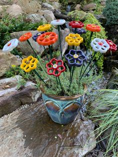 there are many colorful flowers in the pot on the rock garden table and water feature