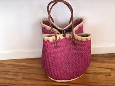 These beautiful pieces are designed in South Africa. Handmade with raffia and featuring leather handles, these bags bring the perfect mix of bohemian chic to everyday wear! Capable of being used as a handbag, basket or storage-this multi-purpose piece is a cannot miss! The double closure top provides a multi-style capability as well! Sizing: 16 inches wide x 12 inches deep x 13 inches high Pink Bohemian Straw Tote Bag, Bohemian Woven Bucket Bag For Shopping, Chic Bags With Bamboo Handle For Market, Chic Bamboo Handle Bag For Market, Chic Market Bags With Bamboo Handle, Pink Bucket Straw Bag With Braided Handles, Pink Bohemian Bucket Bag, Pink Handwoven Bucket Straw Bag, Bohemian Straw Bag With Bamboo Handle For Shopping