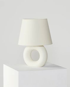 a white lamp sitting on top of a table next to a white square object with a light bulb