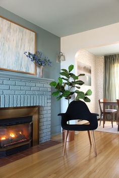 a living room with a fireplace, chair and painting on the wall in front of it