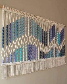 a macrame wall hanging with blue and purple beads